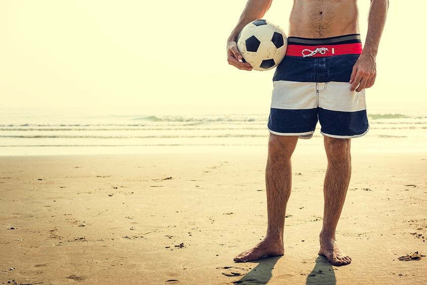 Footballer on beach with football